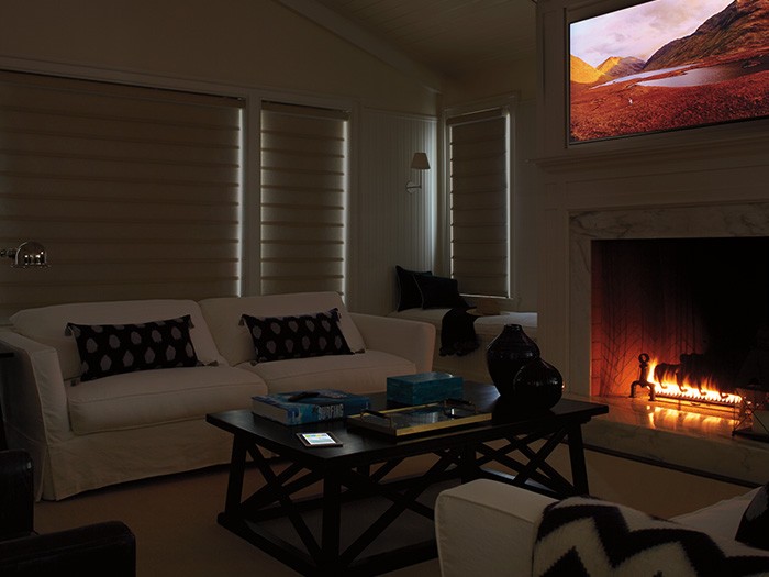 Darkened room with modern furniture and fireplace turned on with logs in place